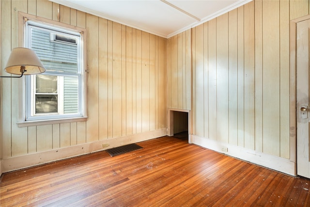 spare room with visible vents, wood-type flooring, and ornamental molding