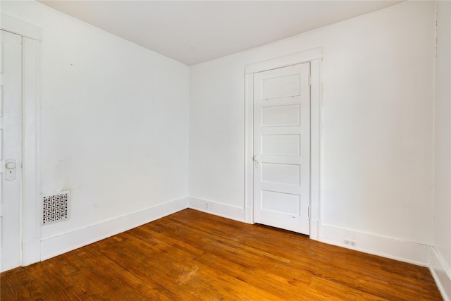 spare room featuring visible vents, baseboards, and wood finished floors