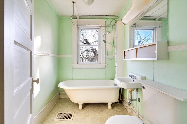 full bath with a freestanding tub, toilet, visible vents, and ornamental molding