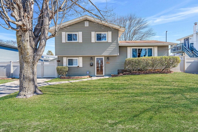 tri-level home with driveway, a front lawn, and fence