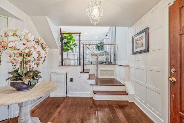 stairs with a notable chandelier, a decorative wall, and wood finished floors