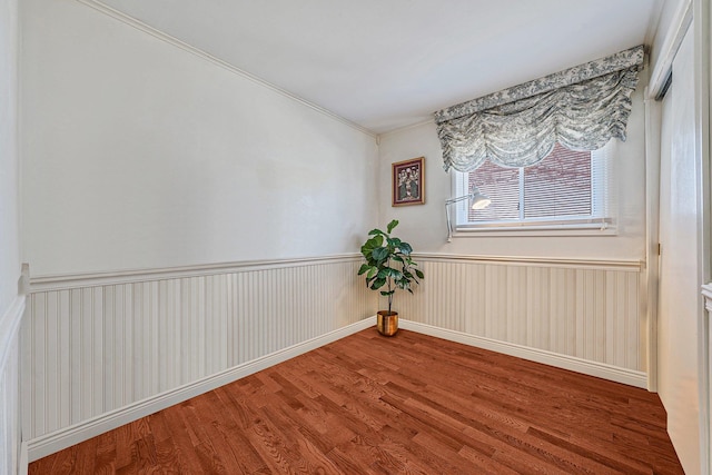 unfurnished room with a wainscoted wall and wood finished floors