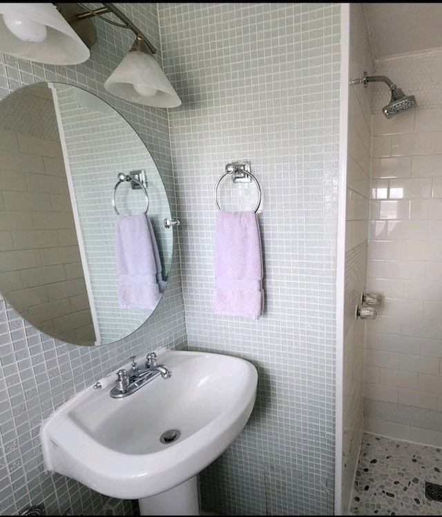 full bath featuring tiled shower, tile walls, and a sink