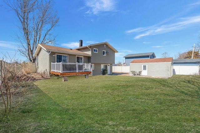 back of property with a lawn, a chimney, a deck, an outdoor structure, and a fenced backyard