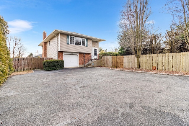 view of front of property with fence, driveway, a chimney, a garage, and brick siding