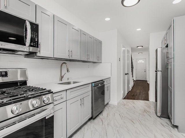 kitchen featuring a sink, stainless steel appliances, light countertops, marble finish floor, and backsplash