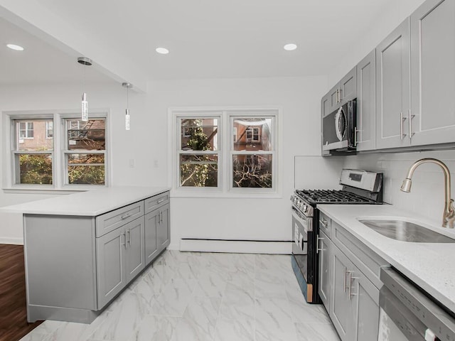 kitchen with gray cabinetry, stainless steel appliances, light countertops, and a sink