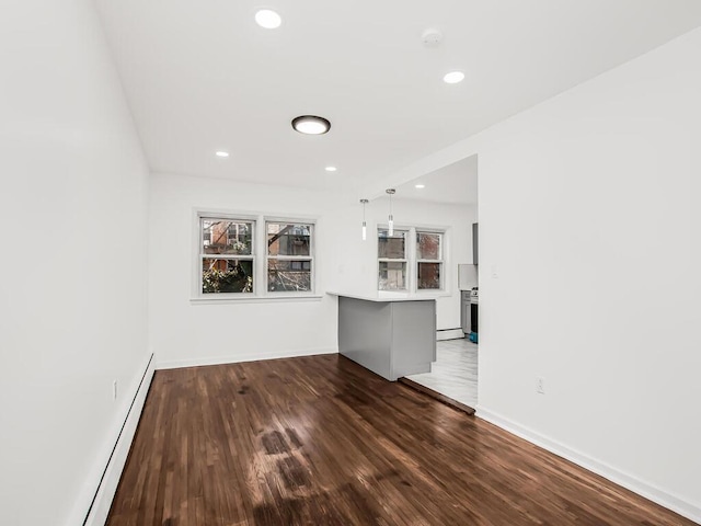 unfurnished living room featuring plenty of natural light, wood finished floors, baseboards, and a baseboard radiator