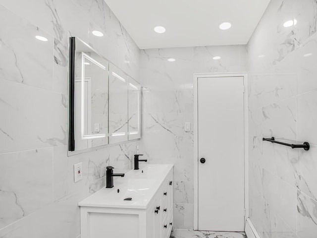 full bath featuring double vanity, recessed lighting, a sink, tile walls, and marble finish floor