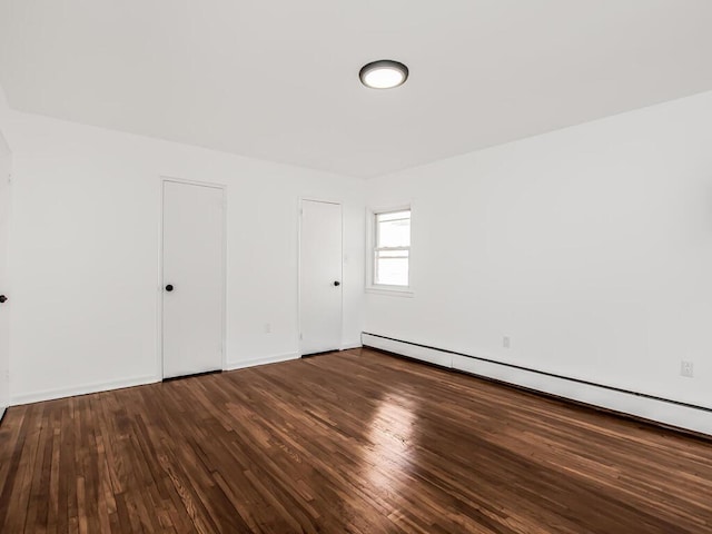 unfurnished room featuring baseboard heating and wood finished floors