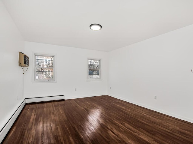 spare room with wood finished floors, a healthy amount of sunlight, baseboards, and baseboard heating