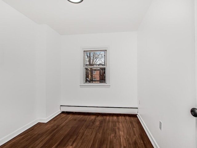 spare room with baseboard heating, baseboards, and wood finished floors