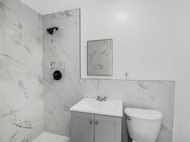 bathroom featuring tiled shower, toilet, and vanity