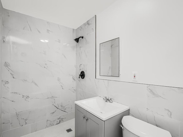 full bathroom with tile walls, toilet, tiled shower, and vanity