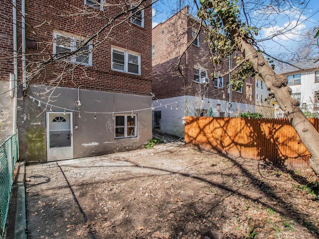 back of house with brick siding and fence