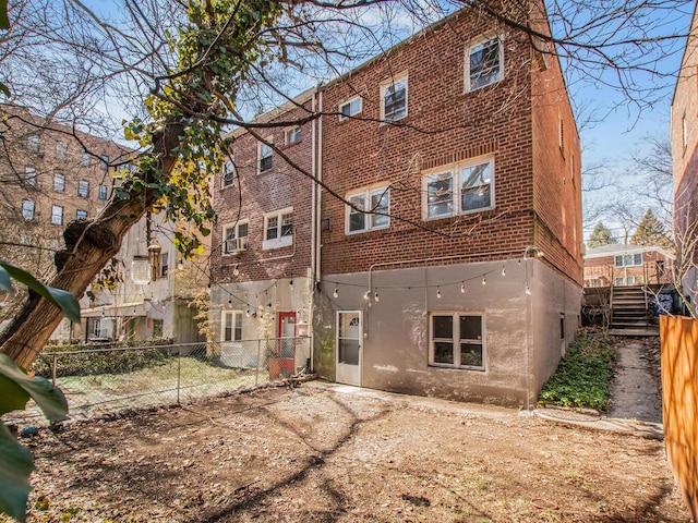 rear view of property with stairs, fence, brick siding, and stucco siding