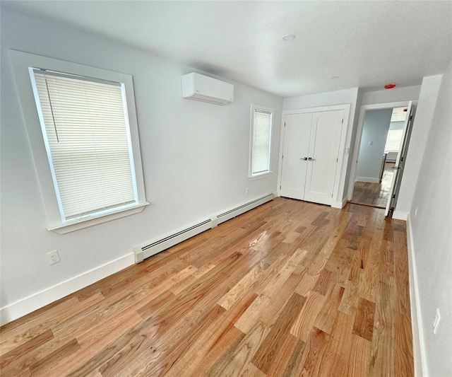 unfurnished bedroom with baseboards, light wood-style floors, a closet, a wall mounted air conditioner, and a baseboard heating unit