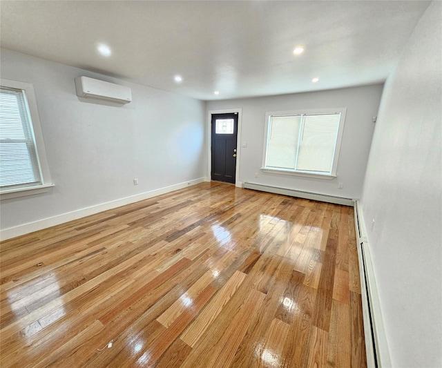 interior space featuring a baseboard heating unit, baseboards, an AC wall unit, recessed lighting, and light wood-style flooring