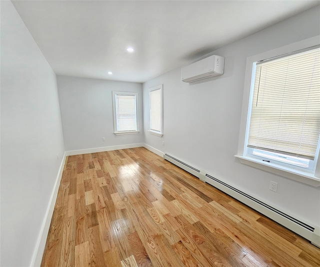 empty room featuring light wood finished floors, a baseboard heating unit, baseboards, a wall mounted air conditioner, and recessed lighting