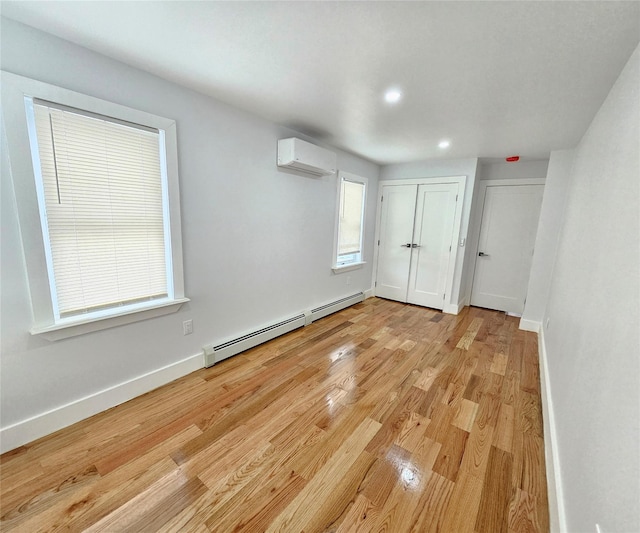 interior space featuring a wall unit AC, baseboards, light wood finished floors, recessed lighting, and baseboard heating