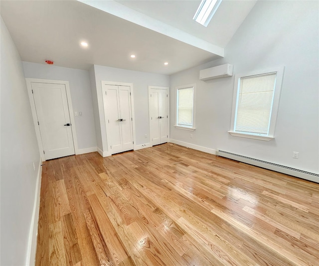 unfurnished bedroom featuring two closets, light wood-style flooring, a wall mounted AC, a baseboard heating unit, and baseboards