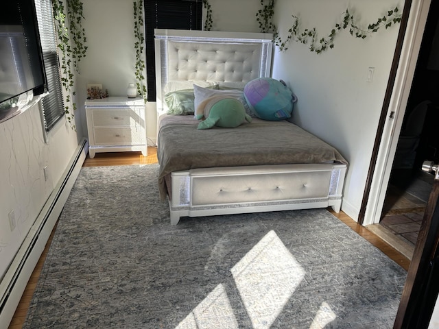 bedroom with wood finished floors and baseboard heating