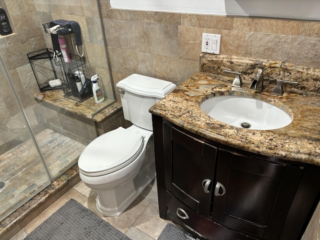 bathroom with tile walls, toilet, vanity, and a shower stall