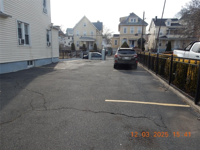 uncovered parking lot featuring a residential view and fence