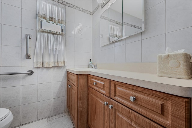 bathroom with toilet, tile walls, and vanity