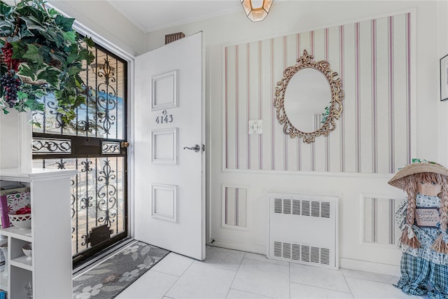 tiled entryway with a wealth of natural light, radiator heating unit, and crown molding