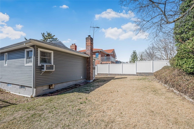 exterior space with cooling unit, fence, a lawn, and a chimney