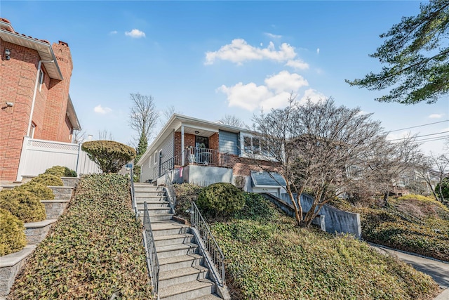 view of front facade with stairway, brick siding, and fence