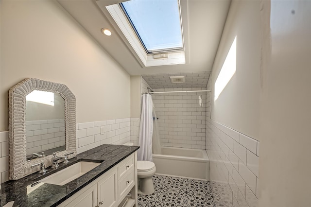 full bath with tile walls, toilet, a skylight, tile patterned floors, and vanity