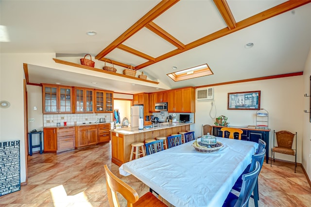 dining area with lofted ceiling with skylight, a wall mounted air conditioner, and baseboards