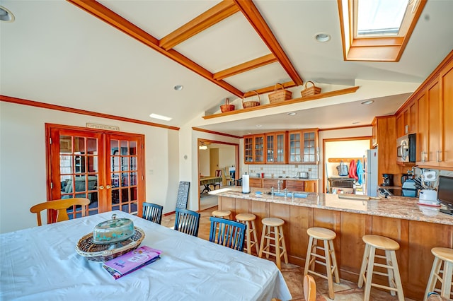 dining room with lofted ceiling with skylight, recessed lighting, and french doors