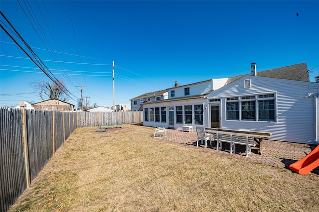 rear view of property featuring a yard, a patio, a fenced backyard, and a sunroom