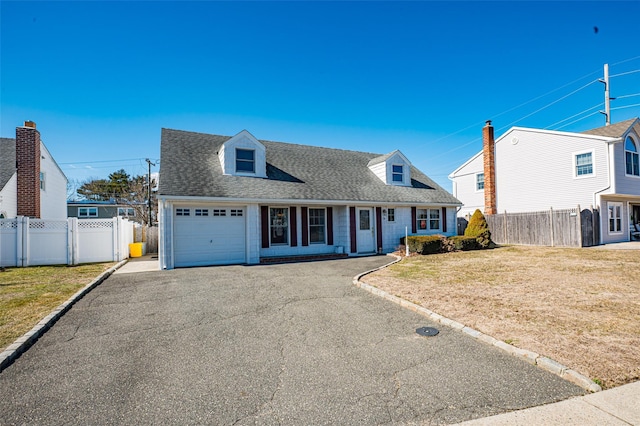 cape cod home with a front yard, fence, driveway, an attached garage, and a shingled roof