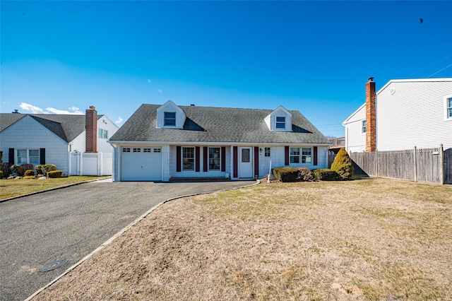 new england style home with aphalt driveway, fence, and a front lawn