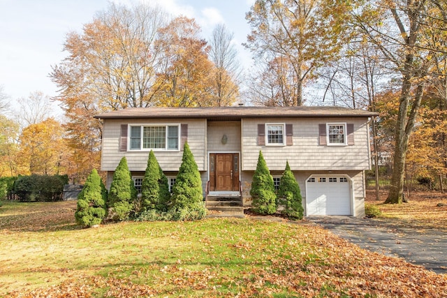 split foyer home featuring a garage, a front yard, and driveway