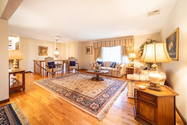 living room with light wood finished floors, visible vents, and baseboards