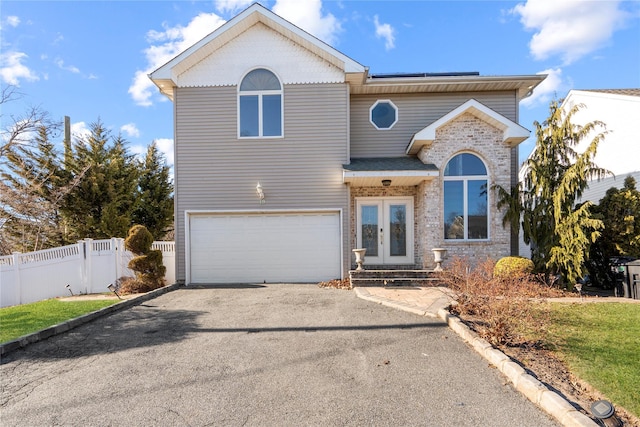 traditional-style home featuring solar panels, fence, aphalt driveway, french doors, and a garage