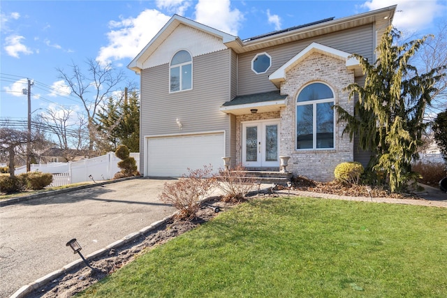 view of front of home with driveway, fence, french doors, a front yard, and a garage