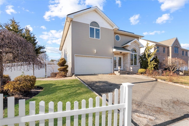 traditional home with a fenced front yard, a front lawn, an attached garage, and driveway