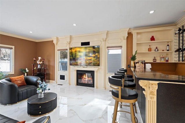 living room with recessed lighting, marble finish floor, a glass covered fireplace, and ornamental molding