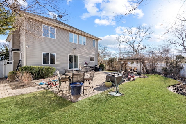 rear view of property featuring a patio, a yard, and fence