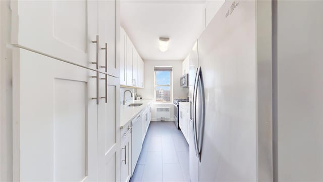 9425 Shore Rd Unit 6C, Brooklyn, NY 11209 - kitchen with a sink, white cabinetry, stainless steel appliances, radiator, and light countertops