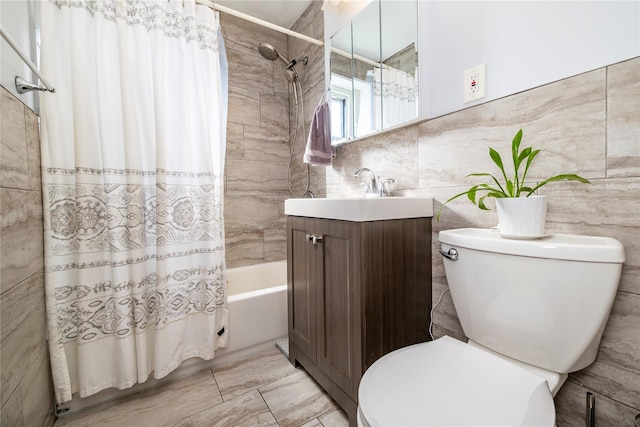 bathroom with tile walls, vanity, toilet, and shower / tub combo