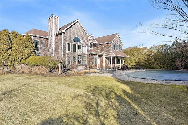 rear view of house with a patio area, a chimney, and a yard