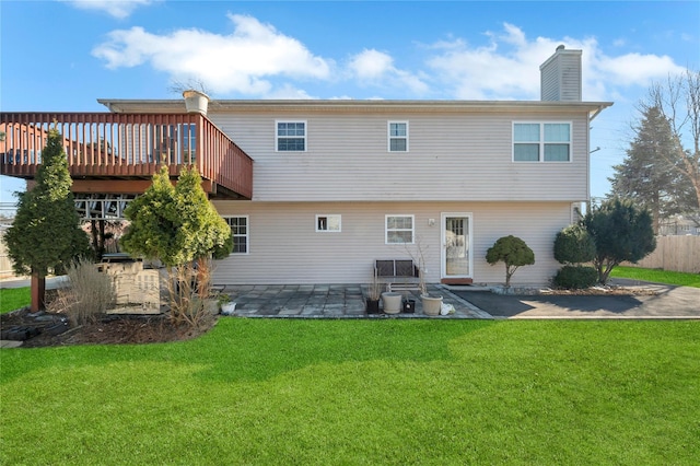 back of property with a deck, a patio, a lawn, and a chimney