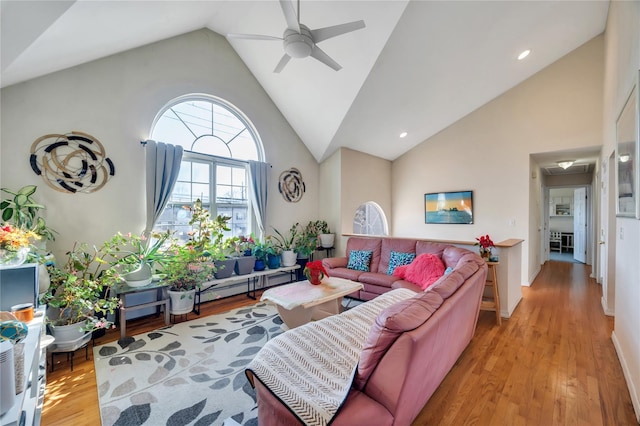 living area with high vaulted ceiling, light wood finished floors, and ceiling fan